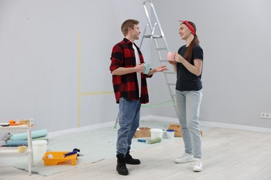 Photo of Couple with cups of coffee having break during renovation in room
