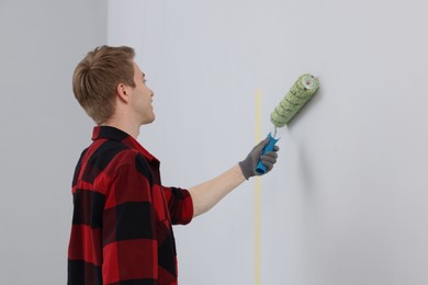 Photo of Man painting wall with roller in room