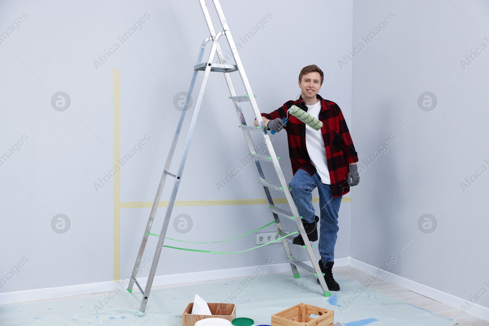 Man with roller and ladder in room Photo of Man with roller and ladder in room