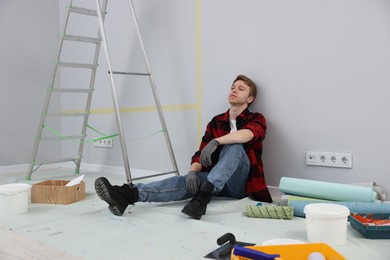 Photo of Tired man having break during renovation in room
