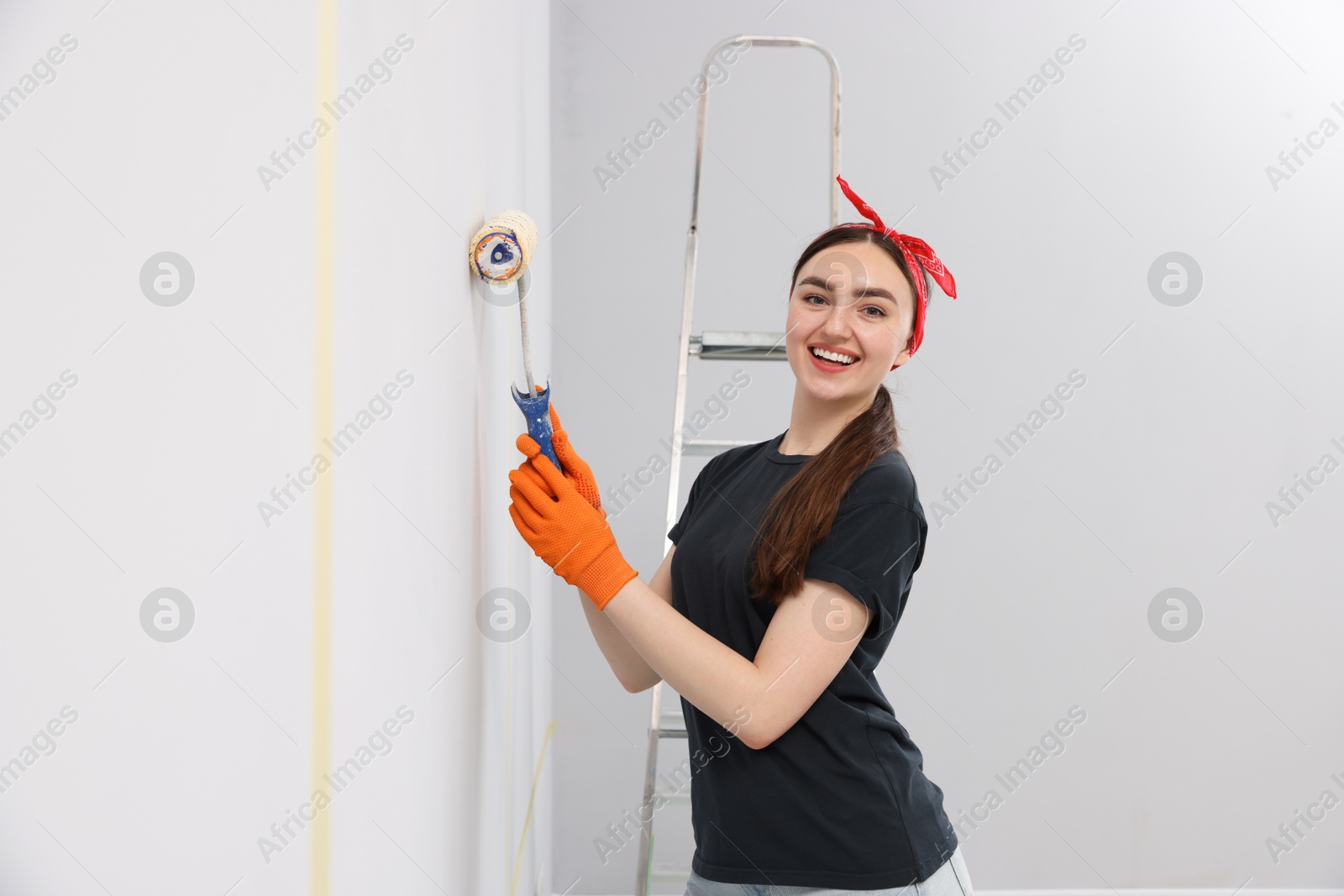 Woman painting wall with roller in room Photo of Woman painting wall with roller in room