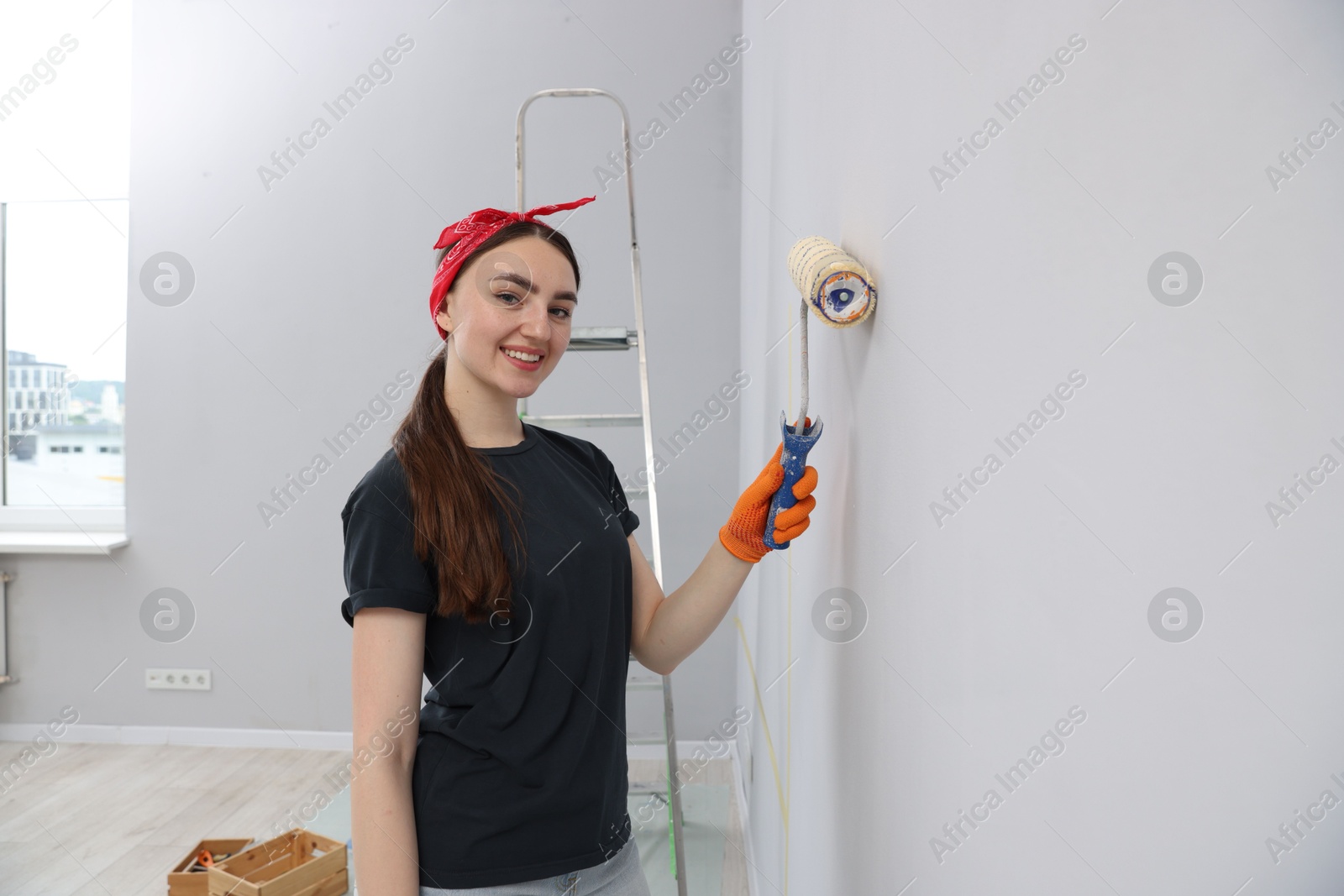 Woman painting wall with roller in room Photo of Woman painting wall with roller in room