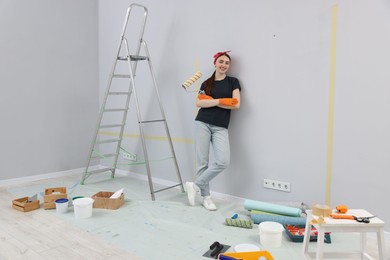 Photo of Woman with roller, ladder and renovation equipment in room