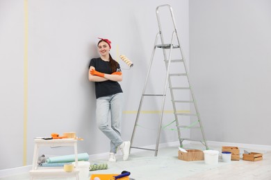 Photo of Woman with roller, ladder and renovation equipment in room