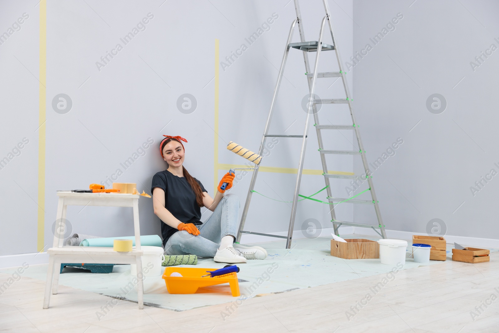Photo of Woman with roller, ladder and renovation equipment in room
