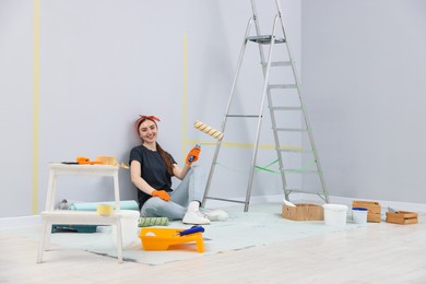 Photo of Woman with roller, ladder and renovation equipment in room