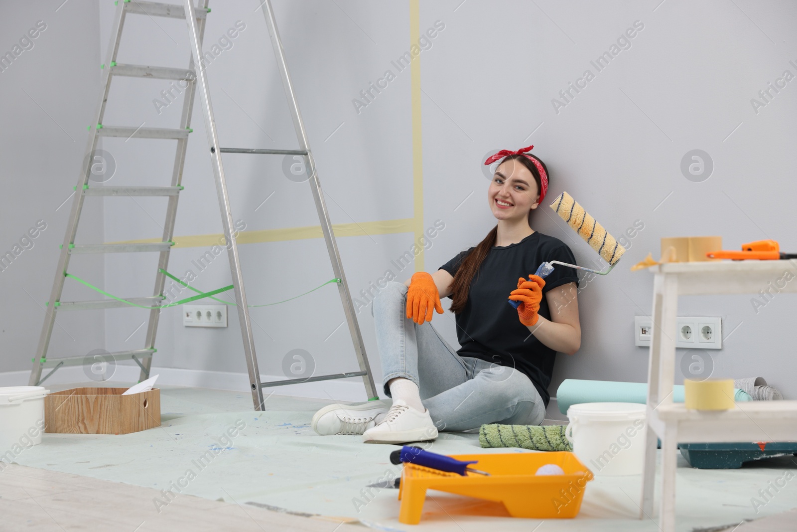 Woman with roller, ladder and renovation equipment in room Photo of Woman with roller, ladder and renovation equipment in room