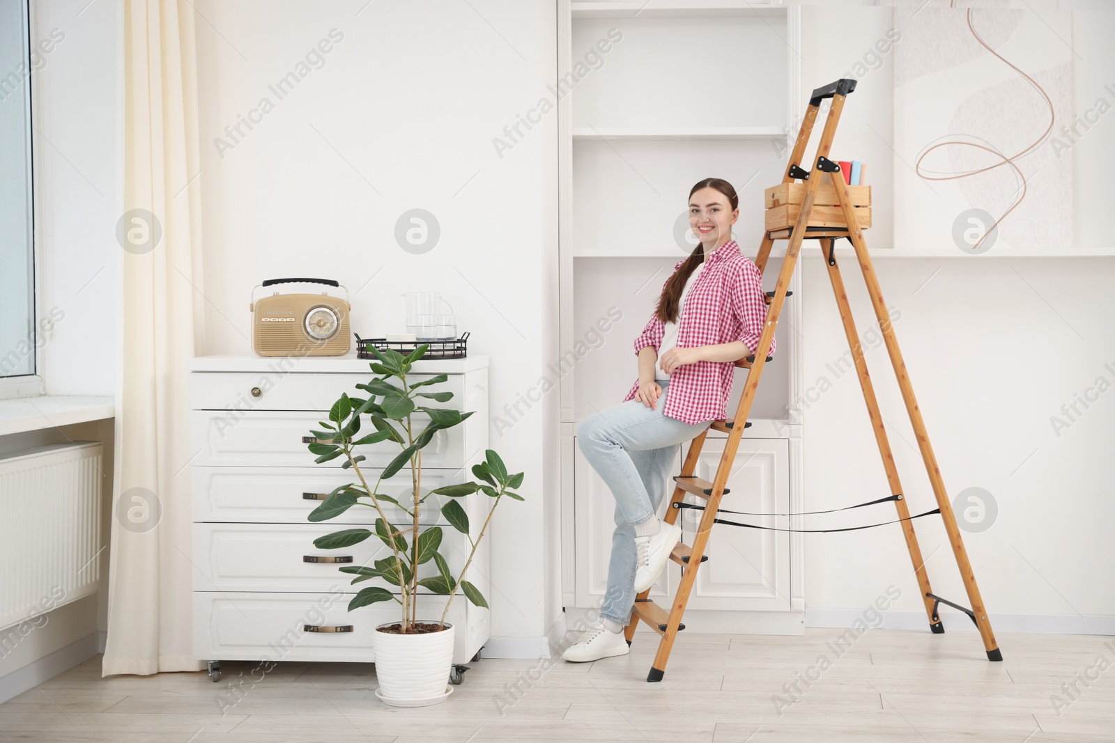 Woman on ladder in new home on moving day Photo of Woman on ladder in new home on moving day