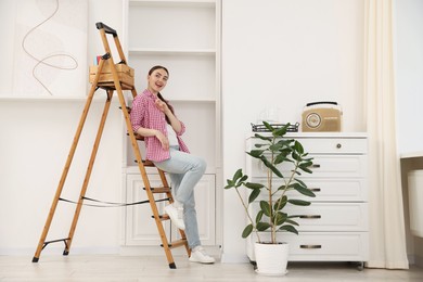 Photo of Woman on ladder in new home on moving day
