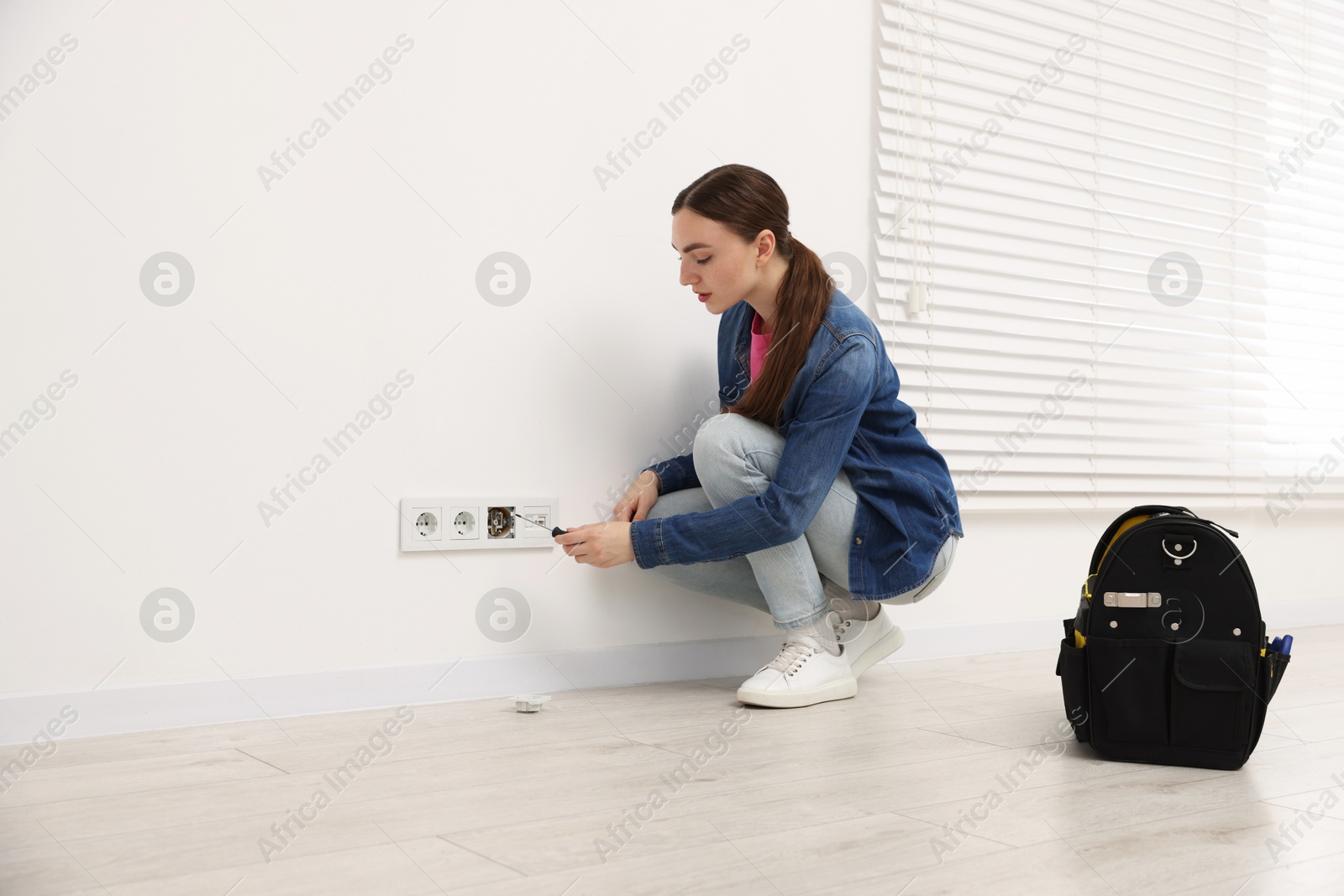 Woman with screwdriver installing new socket at home Photo of Woman with screwdriver installing new socket at home