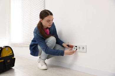 Photo of Woman with screwdriver installing new socket at home