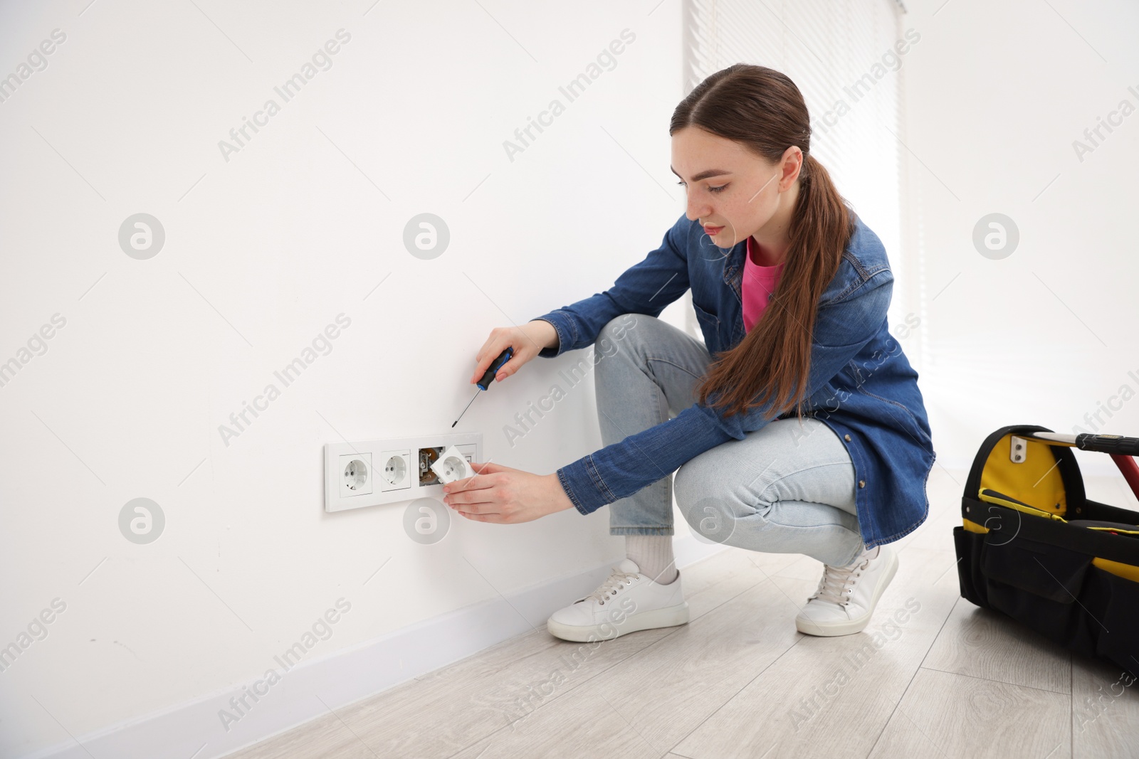 Woman with screwdriver installing new socket at home Photo of Woman with screwdriver installing new socket at home