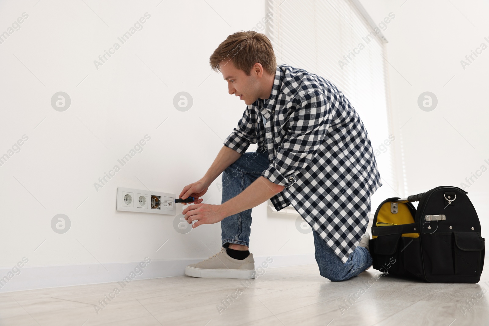 Man with tools installing new socket at home Photo of Man with tools installing new socket at home