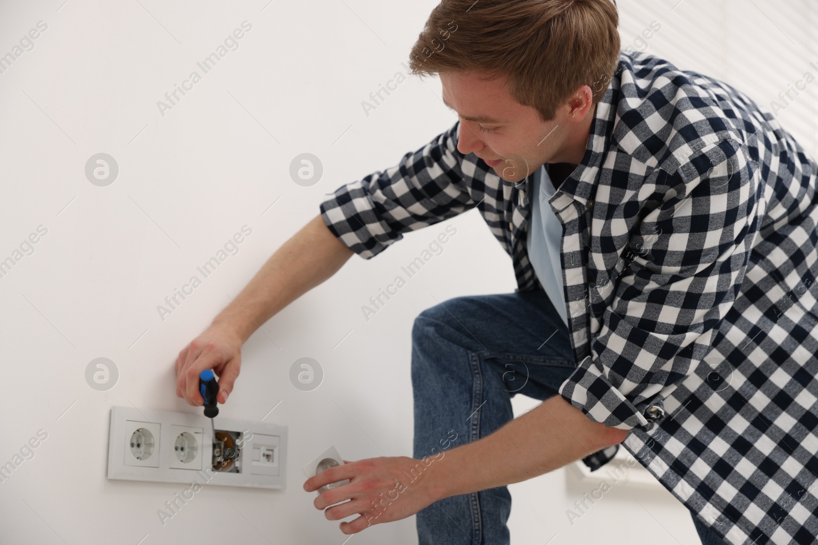 Photo of Man with screwdriver installing new socket at home