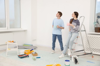 Photo of Couple with cups of coffee having break during renovation at home