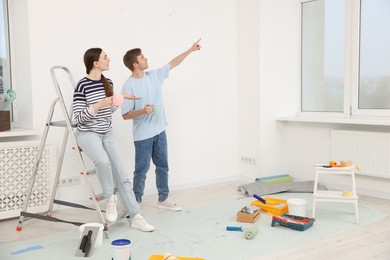 Photo of Couple with cups of coffee having break during renovation at home