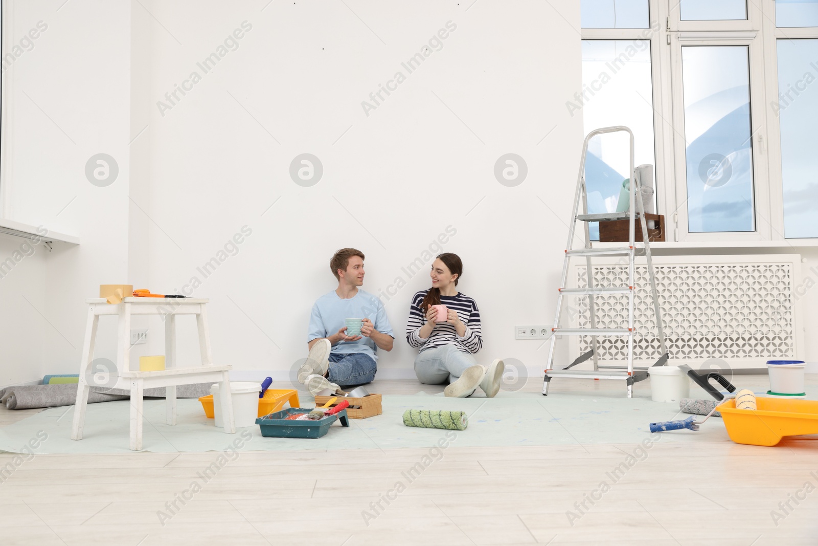 Couple with cups of coffee having break during renovation at home Photo of Couple with cups of coffee having break during renovation at home
