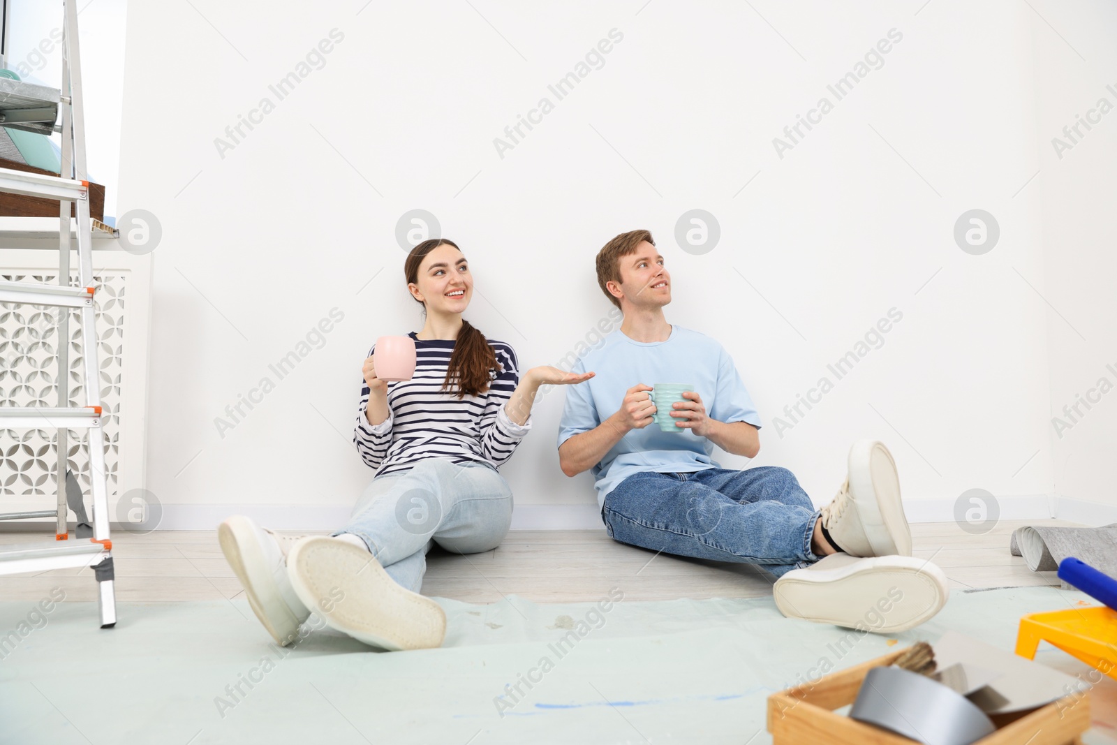Couple with cups of coffee having break during renovation at home Photo of Couple with cups of coffee having break during renovation at home