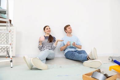 Photo of Couple with cups of coffee having break during renovation at home