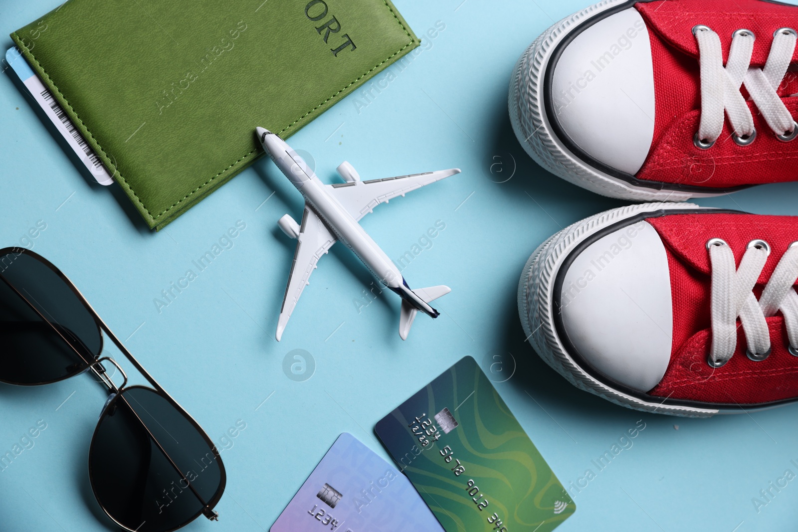 Airplane model, passport, credit cards, sunglasses and sneakers on light blue background, flat lay Photo of Airplane model, passport, credit cards, sunglasses and sneakers on light blue background, flat lay