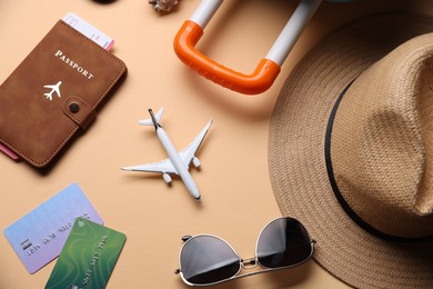 Photo of Airplane model, passport, credit cards, flight ticket and accessories on beige background, flat lay