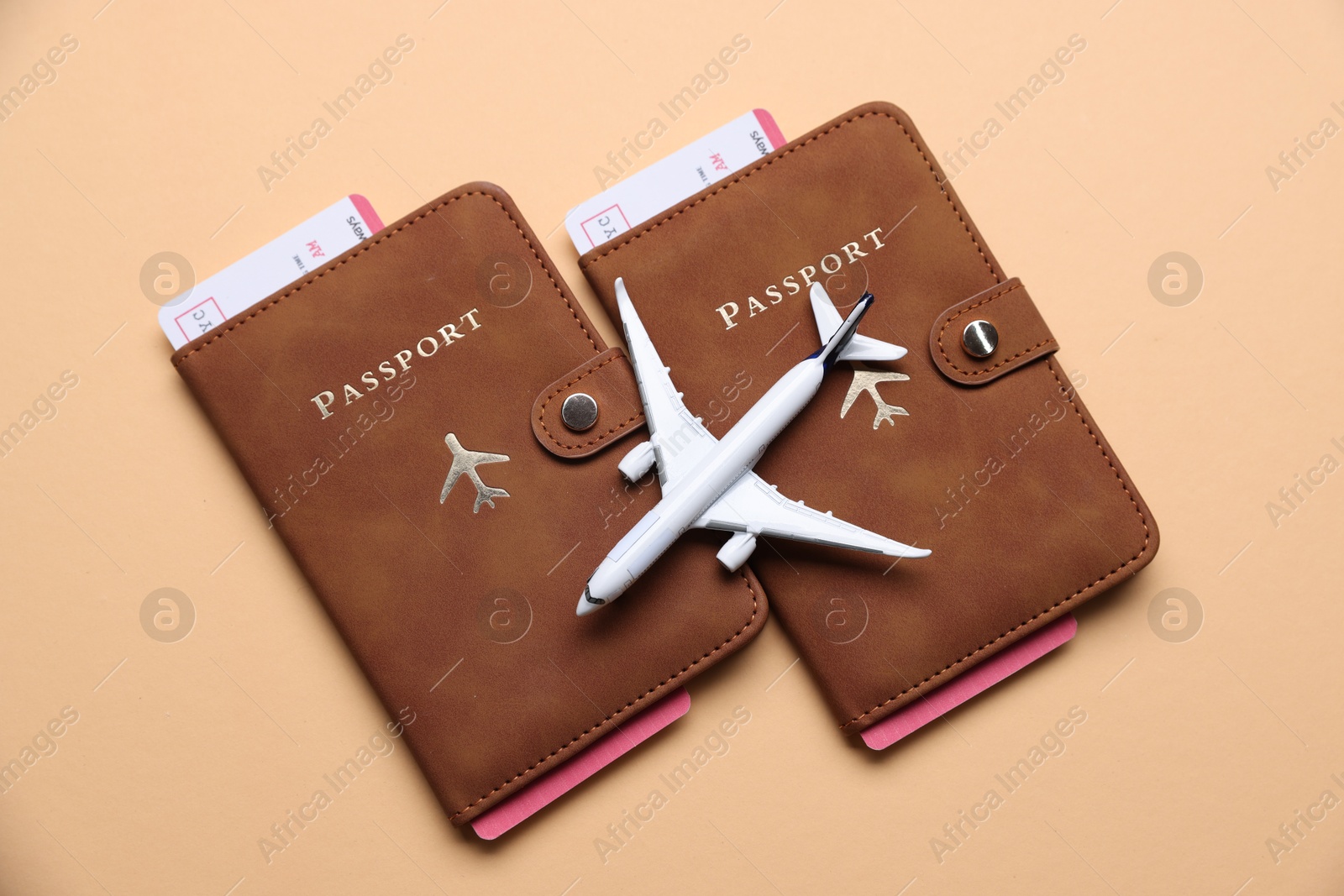 Photo of Airplane model, passports and flight tickets on beige background, flat lay