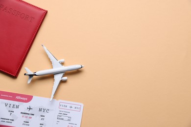 Photo of Airplane model, passport and flight ticket on beige background, flat lay. Space for text