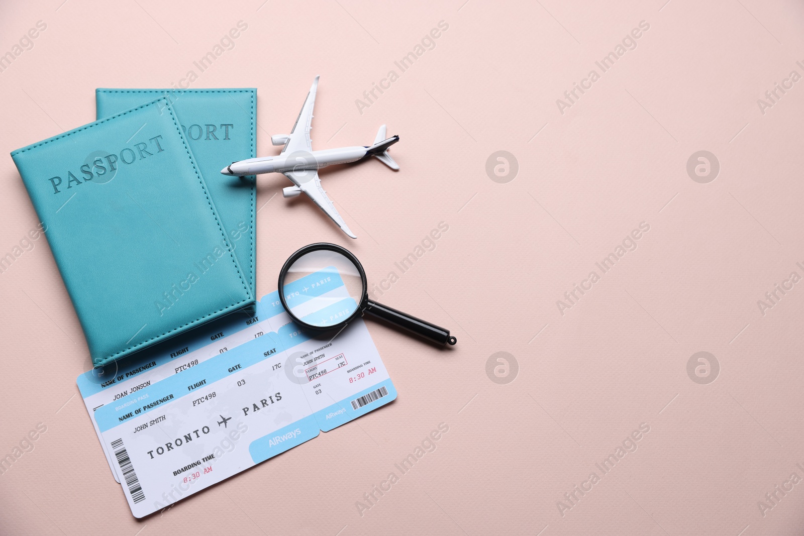 Photo of Airplane model, passports, flight tickets and magnifying glass on beige background, flat lay. Space for text