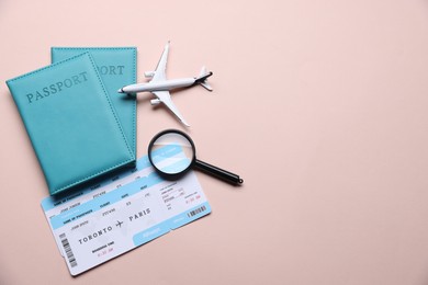 Photo of Airplane model, passports, flight tickets and magnifying glass on beige background, flat lay. Space for text