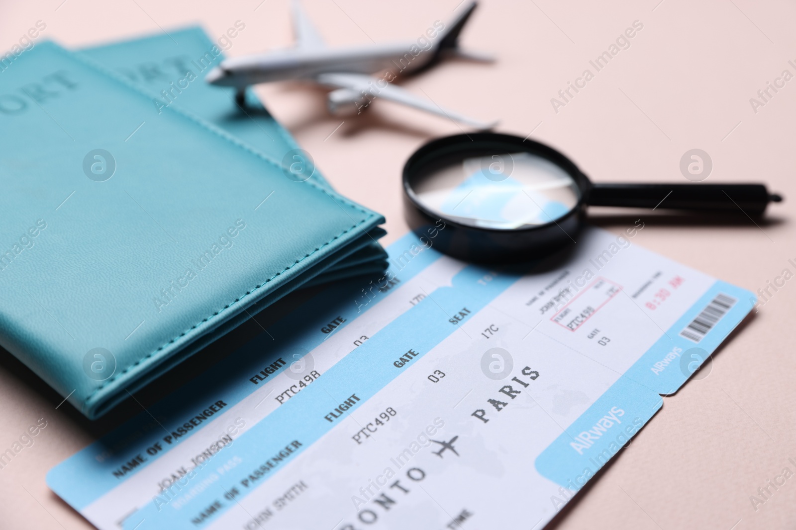 Photo of Flight tickets, passports, airplane model and magnifying glass on beige background, closeup