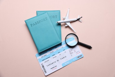Photo of Airplane model, passports, flight tickets and magnifying glass on beige background, flat lay