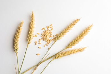 Photo of Wheat spikes and seeds on white background, flat lay