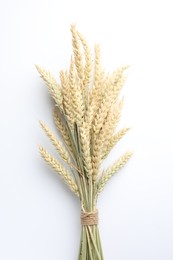 Photo of Bunch of wheat spikes on white background, top view