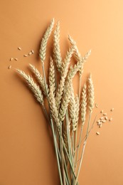 Photo of Many wheat spikes and seeds on golden background, flat lay