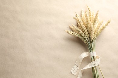 Photo of Bunch of wheat spikes on paper background, top view. Space for text
