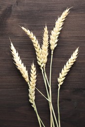 Photo of Many wheat spikes on wooden table, flat lay