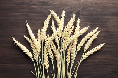 Photo of Many wheat spikes on wooden table, flat lay