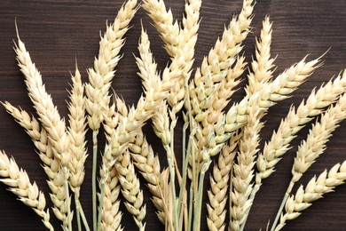 Photo of Many wheat spikes on wooden table, flat lay