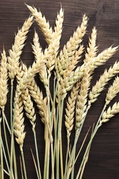 Photo of Many wheat spikes on wooden table, flat lay