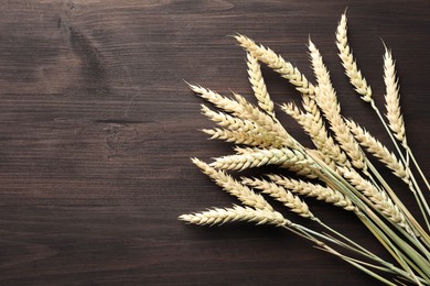 Photo of Many wheat spikes on wooden table, flat lay. Space for text