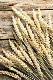 Photo of Many wheat spikes on wooden table, flat lay