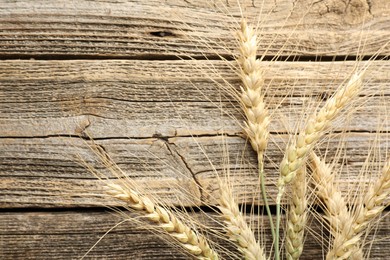 Photo of Many wheat spikes on wooden table, flat lay