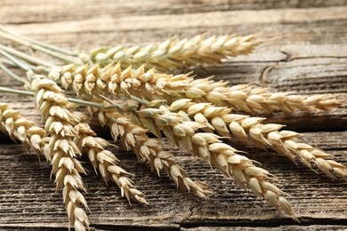 Photo of Many wheat spikes on wooden table, closeup