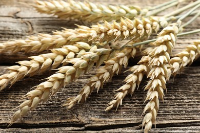 Photo of Many wheat spikes on wooden table, closeup