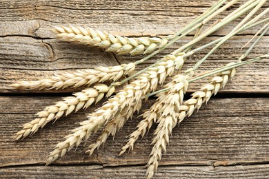 Photo of Many wheat spikes on wooden table, flat lay