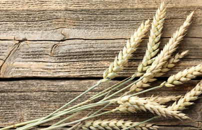 Photo of Many wheat spikes on wooden table, flat lay. Space for text