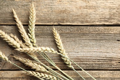 Photo of Many wheat spikes on wooden table, flat lay. Space for text