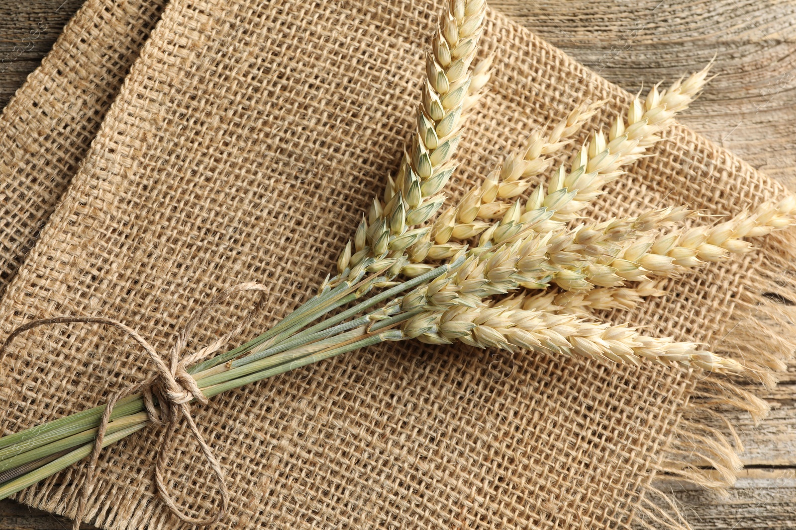 Bunch of wheat spikes on wooden table, top view Photo of Bunch of wheat spikes on wooden table, top view