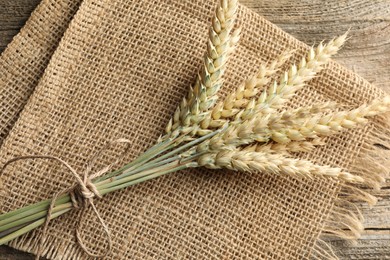 Photo of Bunch of wheat spikes on wooden table, top view
