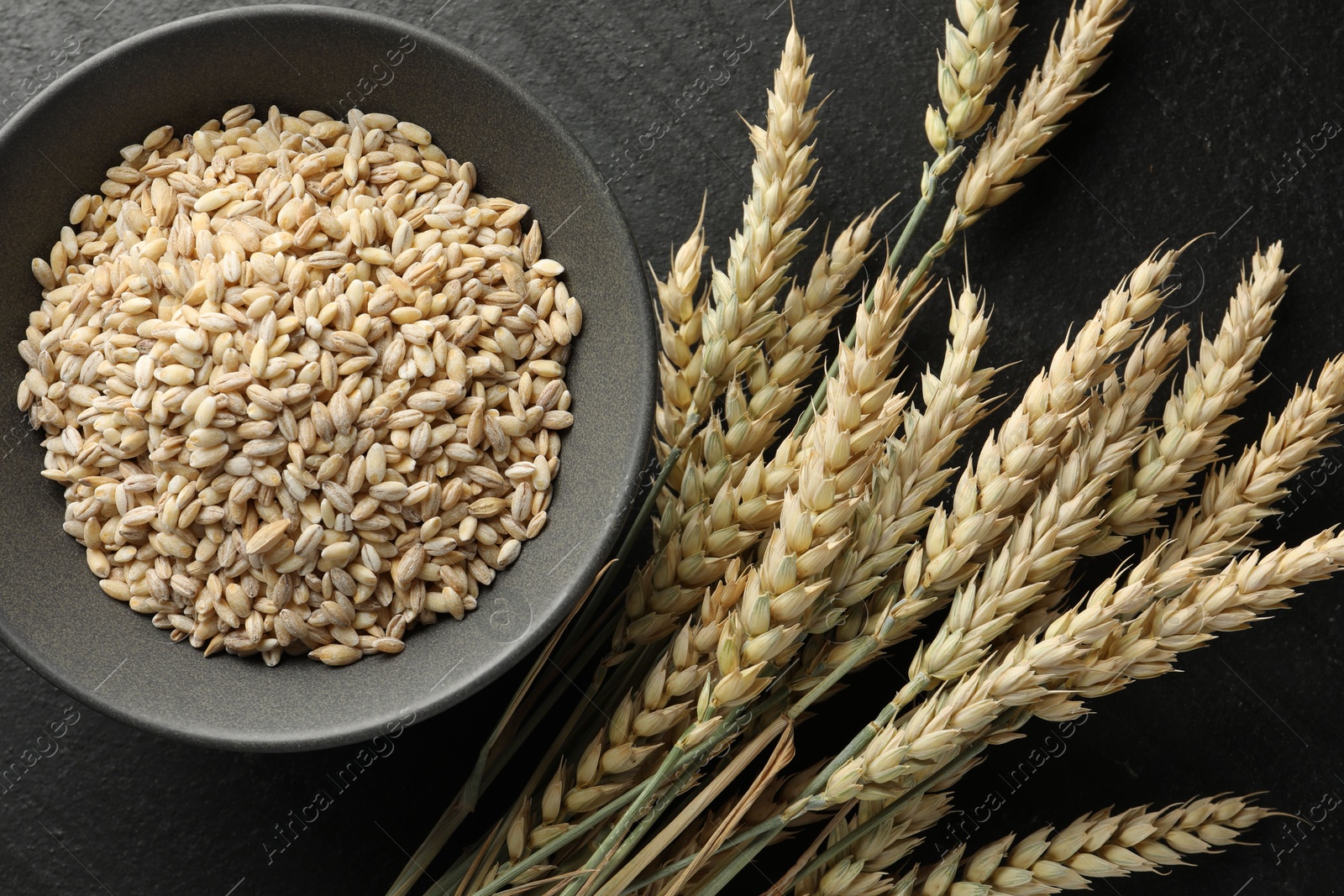 Many wheat spikes and grains on black table, flat lay Photo of Many wheat spikes and grains on black table, flat lay